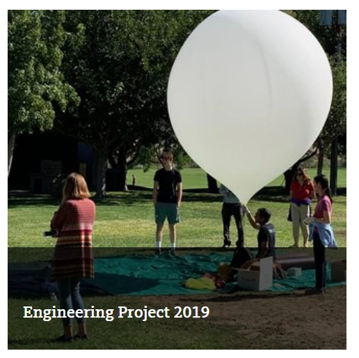Young people and adults preparing a large white balloon outdoors for the 2019 engineering project.